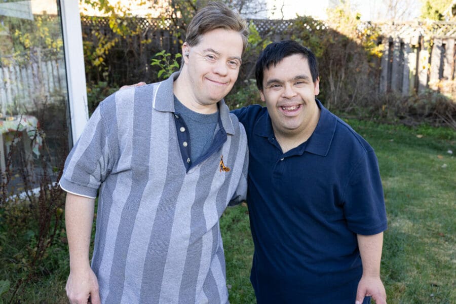 Andrew and Ravi left to right. [Two men outdoors with their arms around each other smiling]