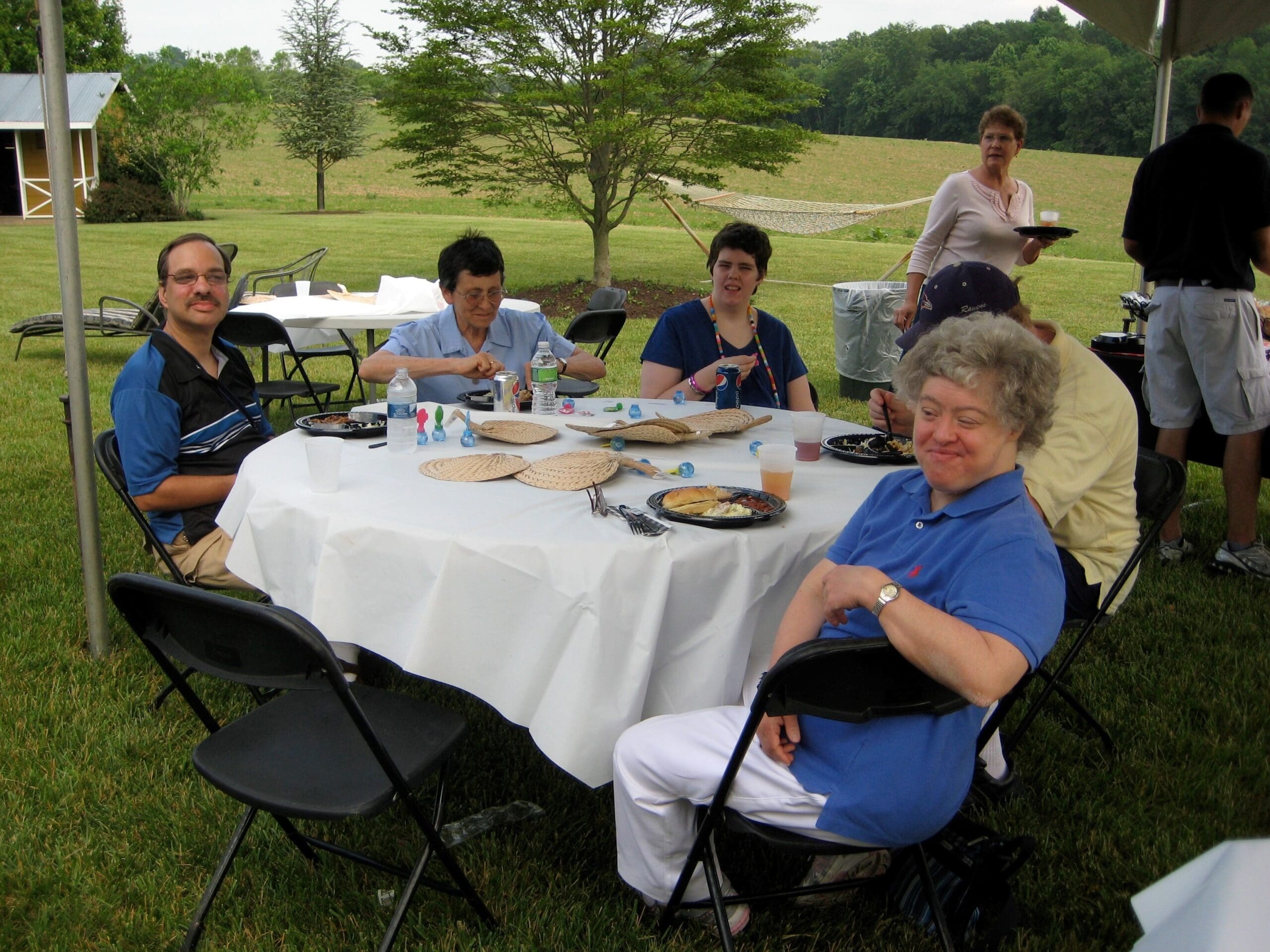 A group of friends sit at an outdoor table to enjoy a picnic together.