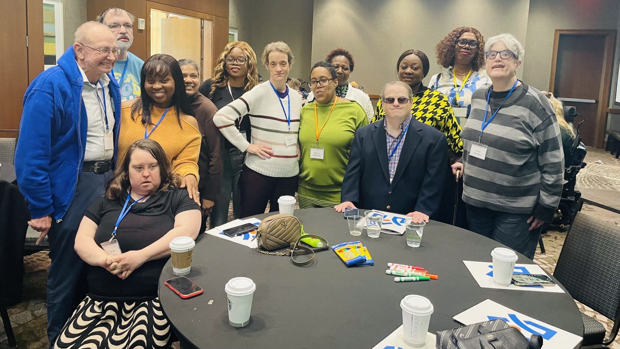 A group of people gather together around a conference room table