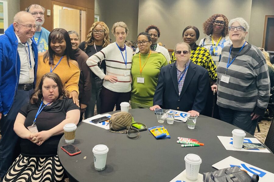 A group of people gather together around a conference room table