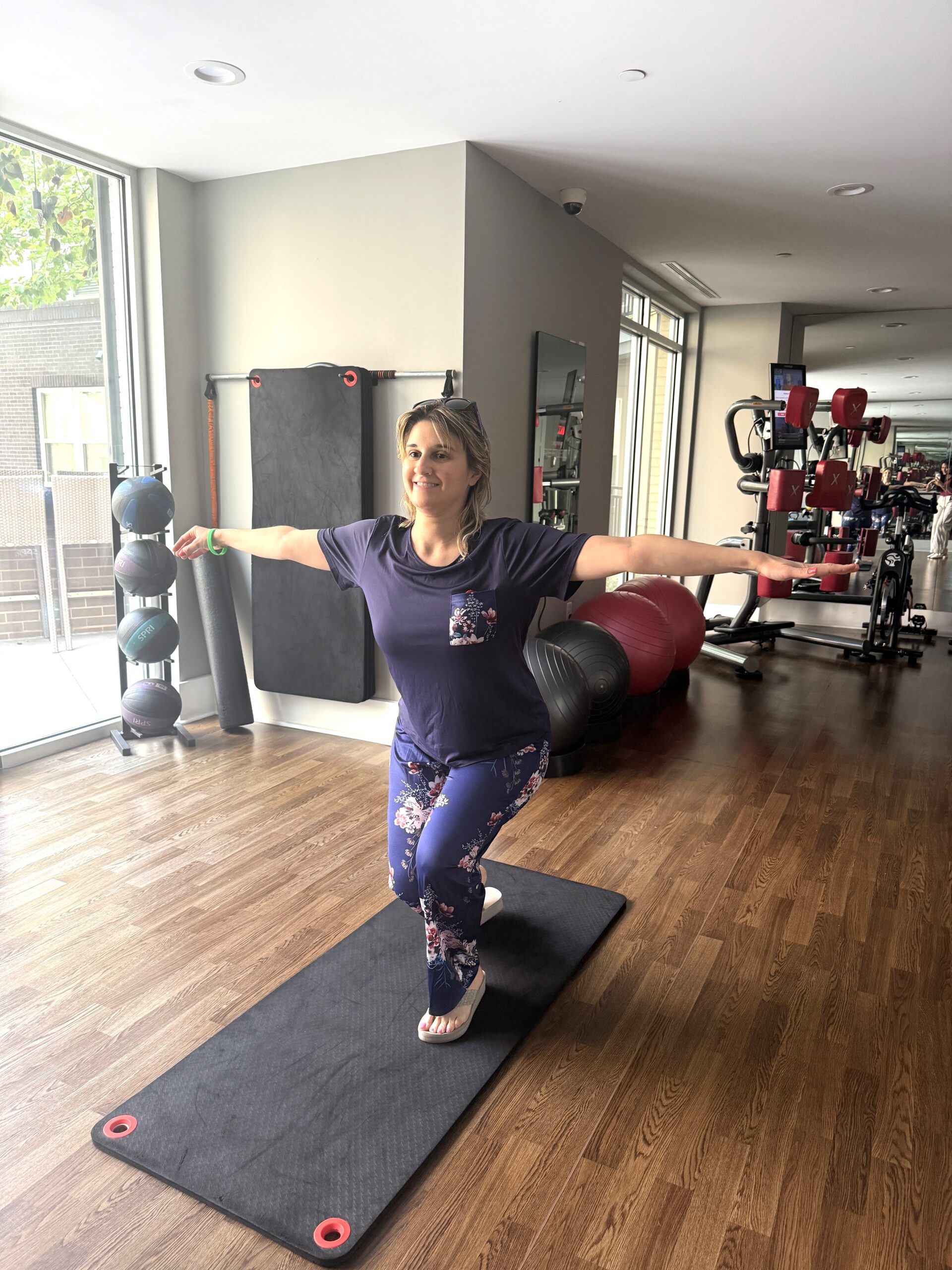 A woman practices yoga on a mat in a gym