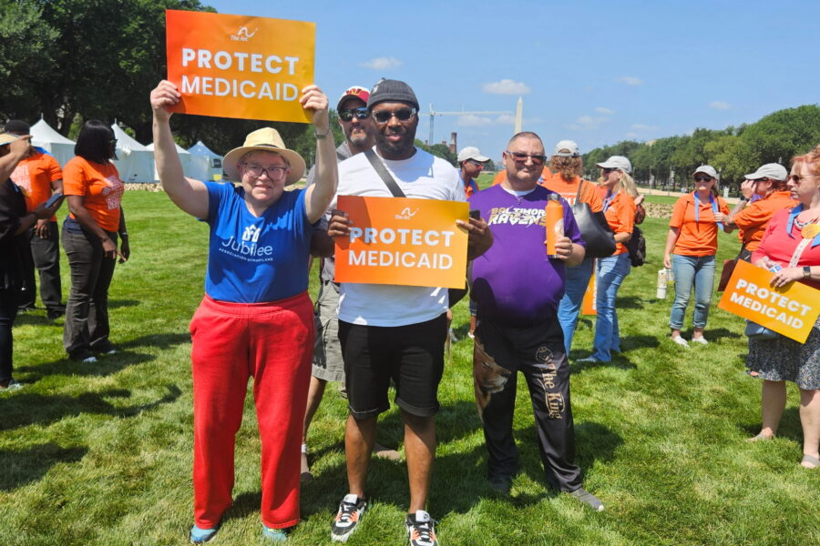 Four people stand on the National Mall in Washington, DC holding up signs that say Protect Medicaid