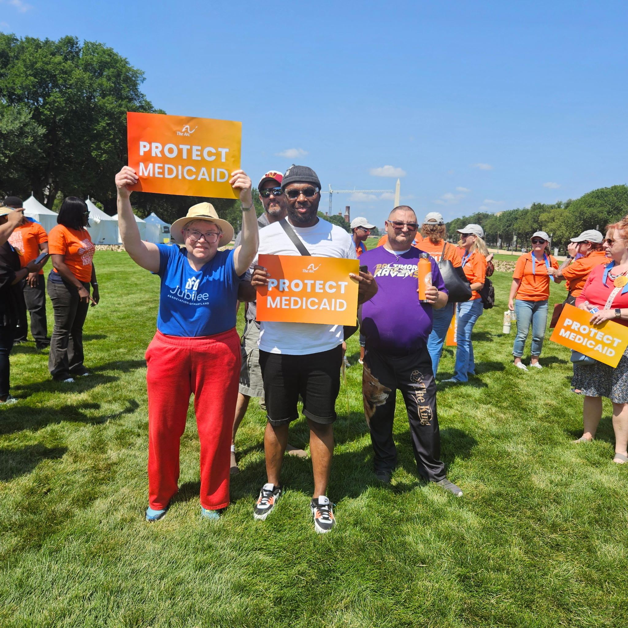 Four people stand on the National Mall in Washington, DC holding up signs that say Protect Medicaid