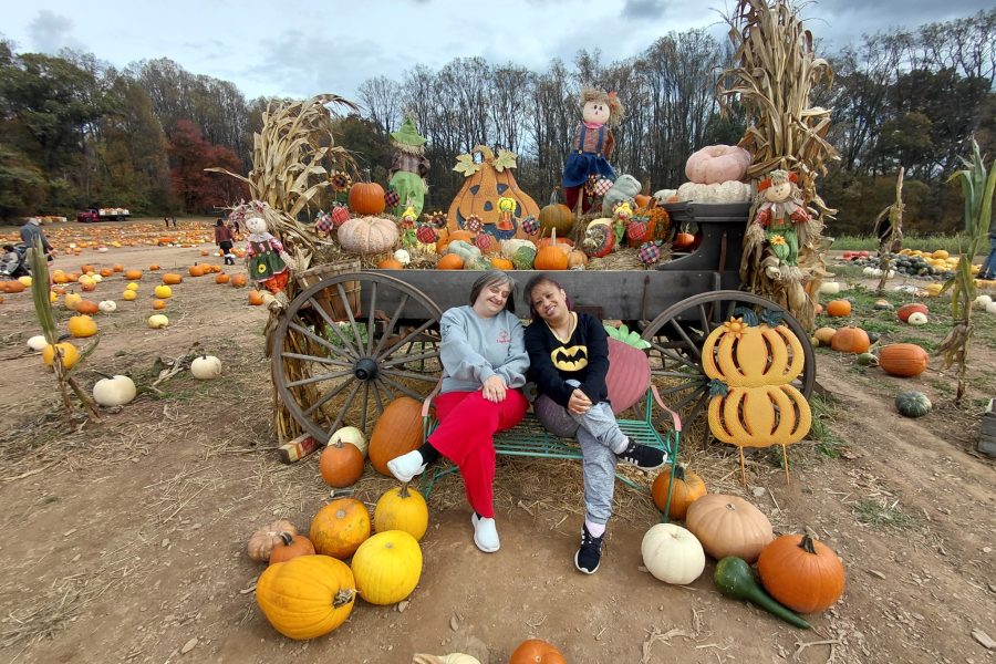 Two adult women pose in a pumpkin patch. Fall fun photo