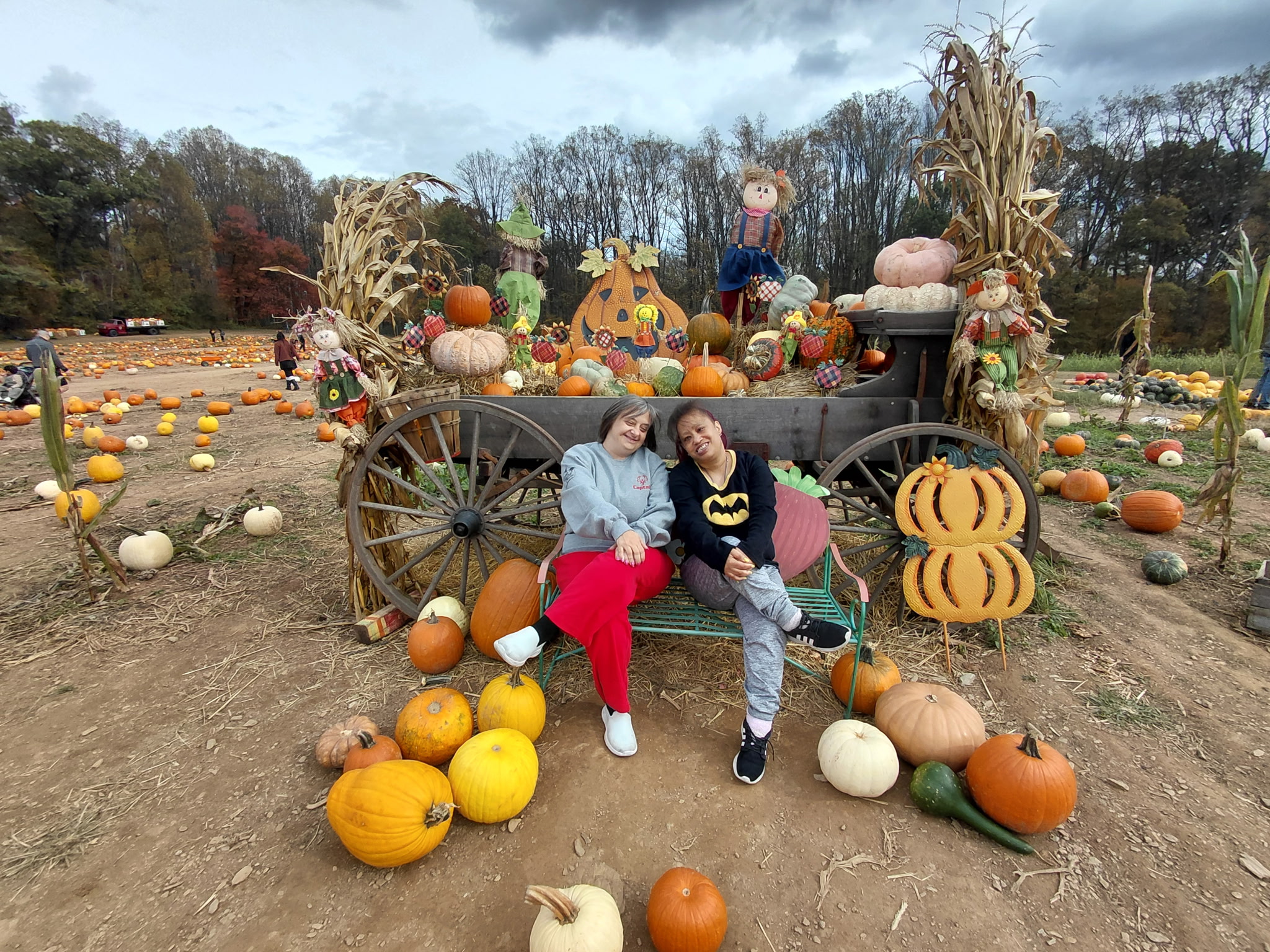Two adult women pose in a pumpkin patch. Fall fun photo