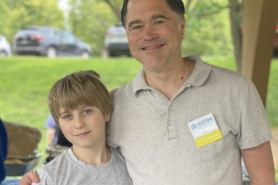 A man and young boy (father and son) at a cookout wearing volunteer name tags.