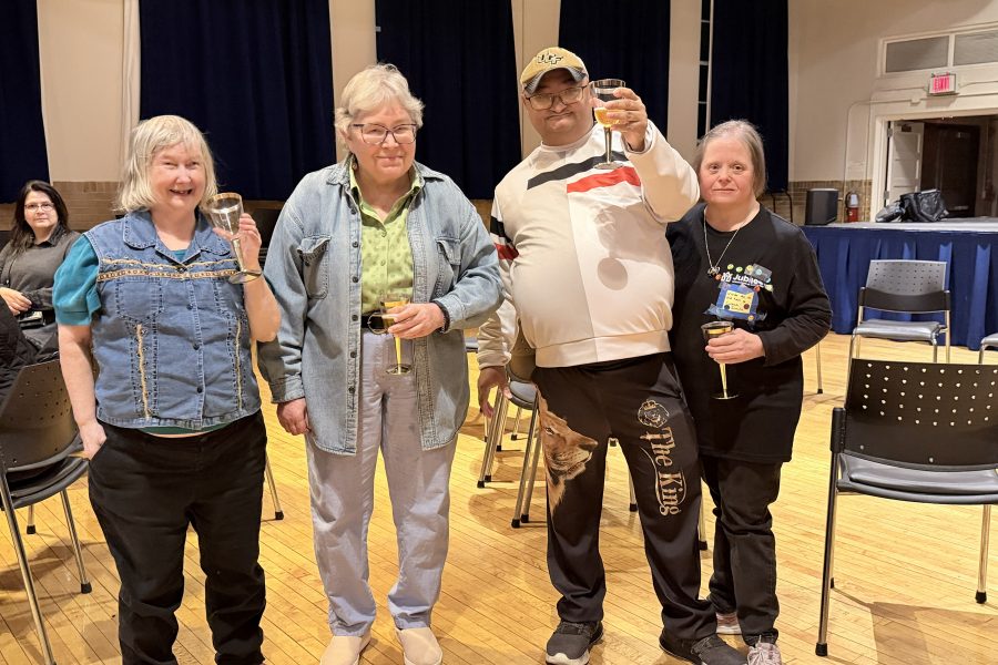 Four people stand together in a town hall.