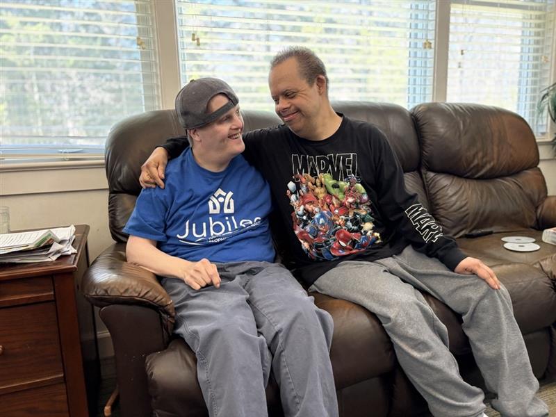 Two men relax on a couch together. [Jubilee housemates Anthony and John[