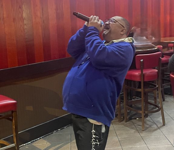 A man with a microphone belts out a song at Karaoke