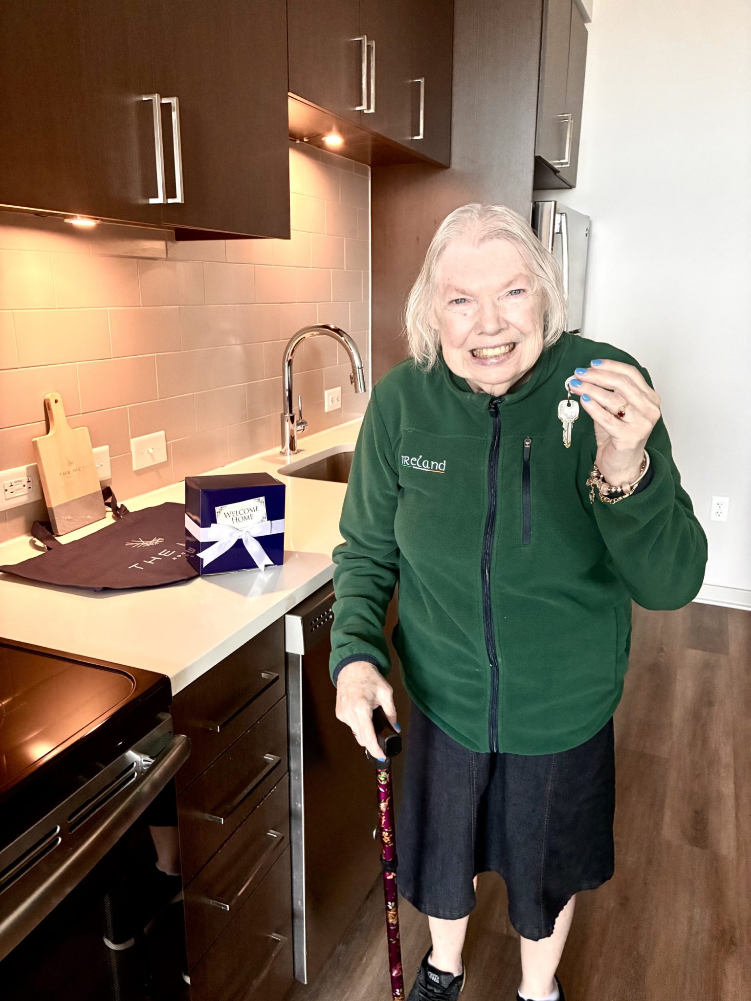 A woman smiles and holds up the keys to her new apartment