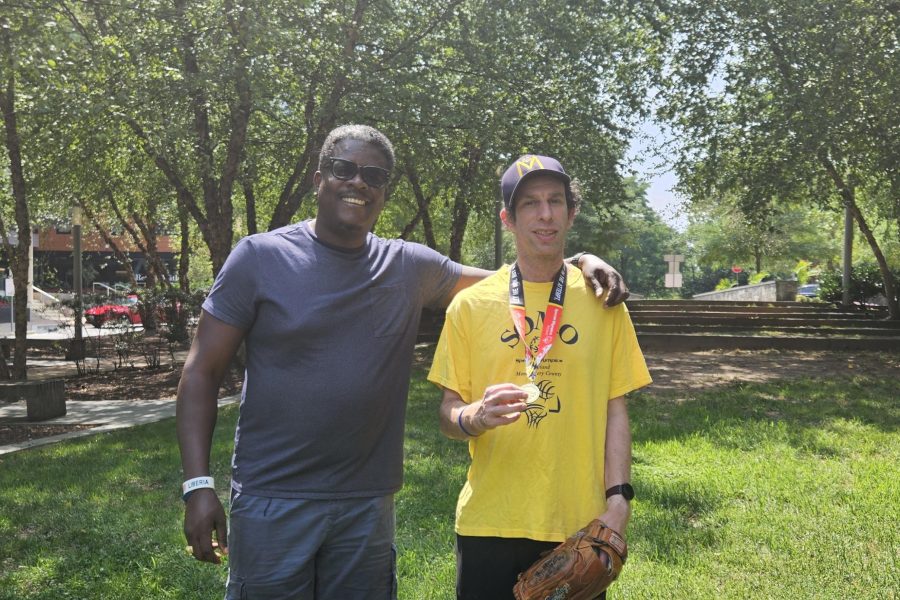Fulkra Cassell and Ben Levy celebrate his softball wins. [two men with their arms around each other. One holds up a medal]