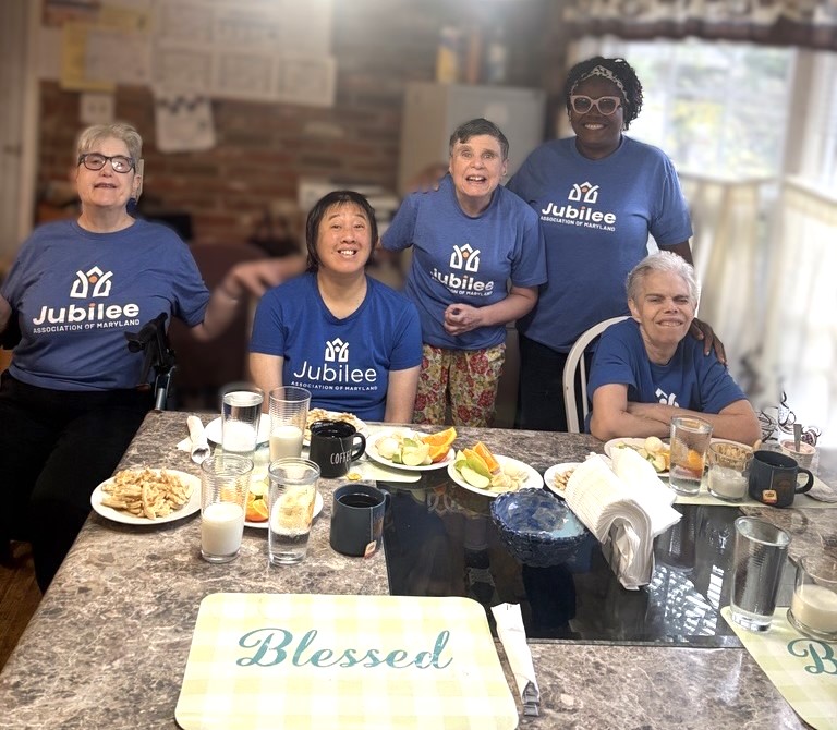 Friends gather around a kitchen table to enjoy Friendsgiving.