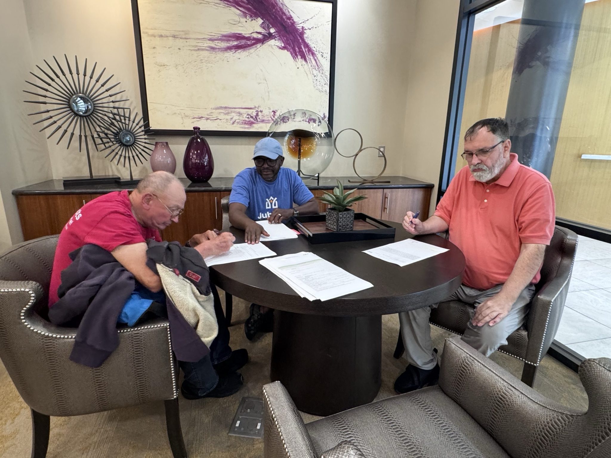 Two men sign a lease for their apartment while Jubilee support staff assist.